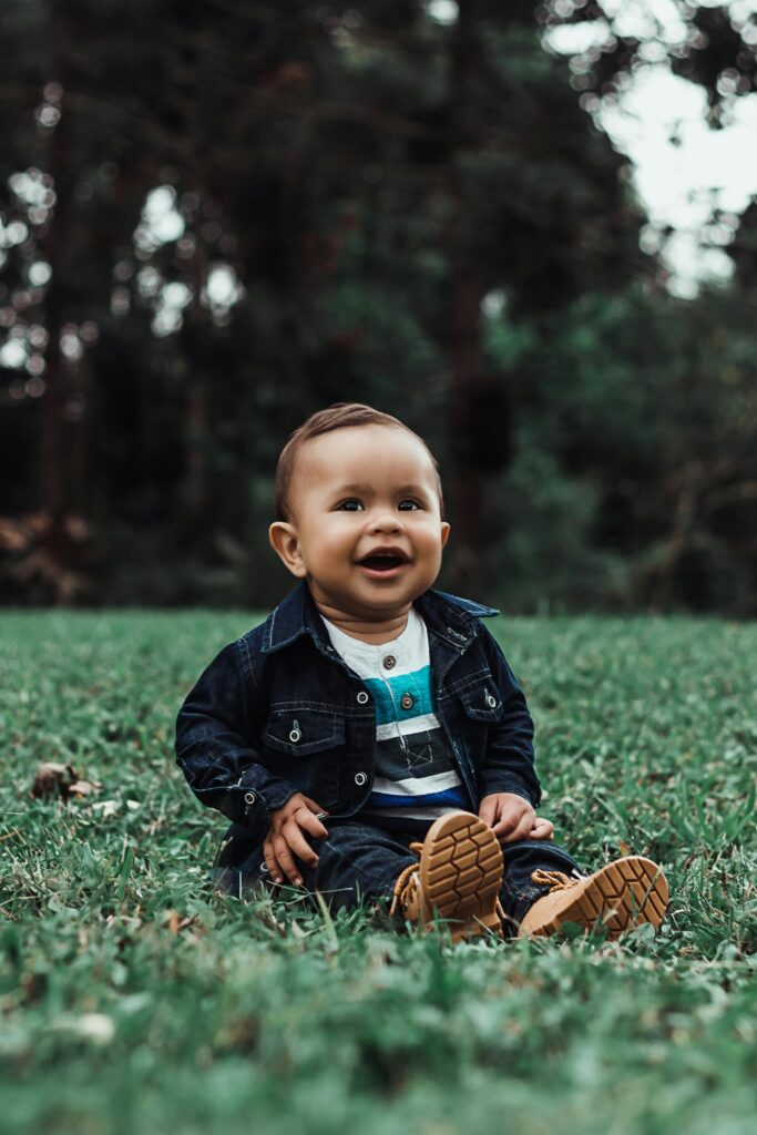 Cute baby sitting and smiling on grass in São Paulo park, Brazil.
